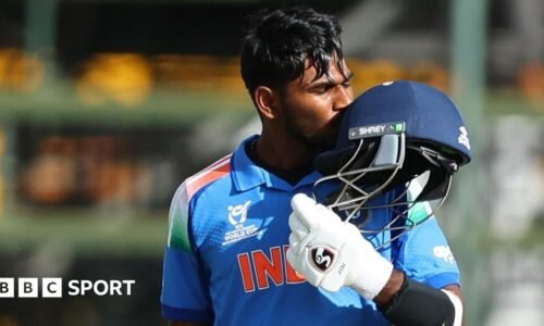 Aaron George celebrates his century by kissing his helmet