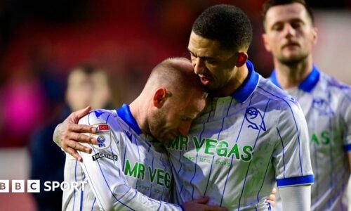 Former Sheffield Wednesday captain Barry Bannan, wearing the club's away shirt of white with royal blue collar and vertical pinstripes, is comforted by team-mate Liam Palmer after a game