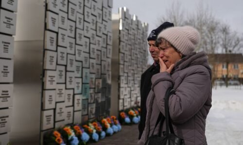 Relatives of those killed during the Russian occupation react at the Wall of Remembrance during a ceremony to mark the fourth anniversary of the Russian invasion of Ukraine, in Bucha, Ukraine, Tuesday, Feb. 24, 2026. (AP Photo/Sergei Grits)