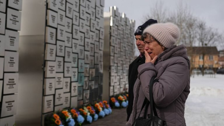 Relatives of those killed during the Russian occupation react at the Wall of Remembrance during a ceremony to mark the fourth anniversary of the Russian invasion of Ukraine, in Bucha, Ukraine, Tuesday, Feb. 24, 2026. (AP Photo/Sergei Grits)