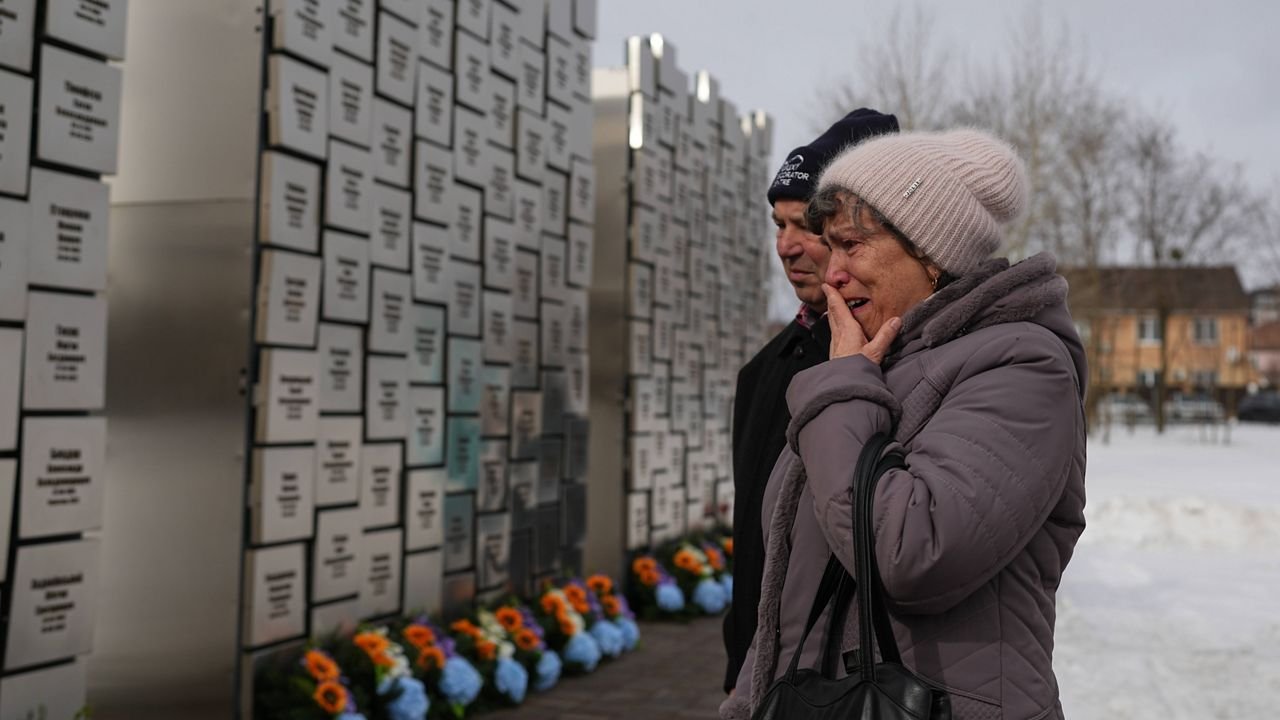 Relatives of those killed during the Russian occupation react at the Wall of Remembrance during a ceremony to mark the fourth anniversary of the Russian invasion of Ukraine, in Bucha, Ukraine, Tuesday, Feb. 24, 2026. (AP Photo/Sergei Grits)