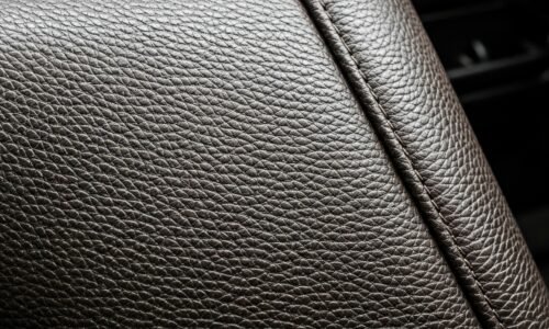 An extreme close-up photograph of the pebbled leather interior of an Alaskan off-road vehicle, capturing the rugged texture and earthy tones of the materials in a dramatic, artistic composition.