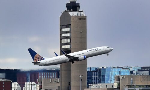 The Logan Airport control tower looms large as a United Airlines jet takes off in Boston.