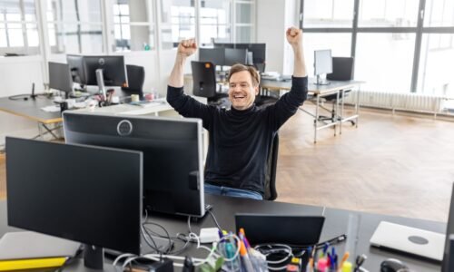 Joyful businessman celebrating success at workplace in office