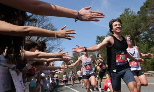 Runners react as Wellesley College students reach out to high-five as they pass during the Boston Marathon on April 21, 2025.