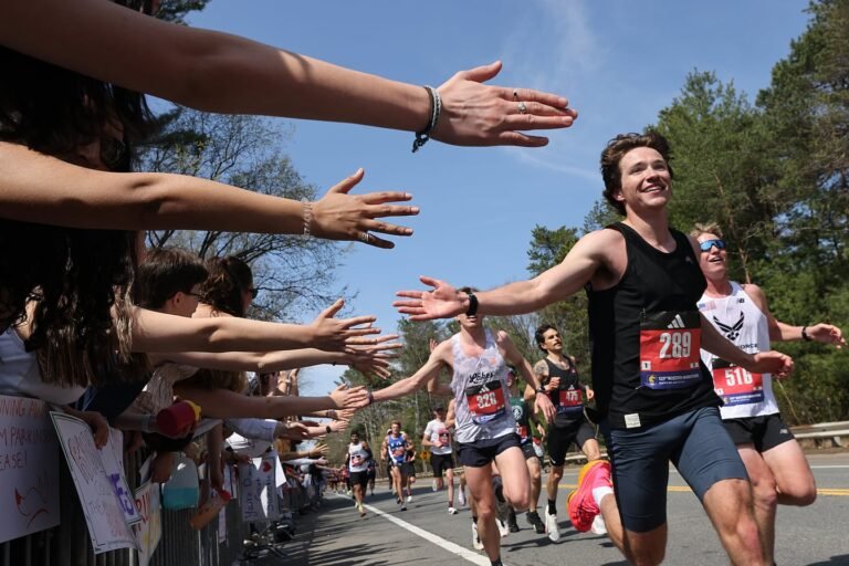 Runners react as Wellesley College students reach out to high-five as they pass during the Boston Marathon on April 21, 2025.