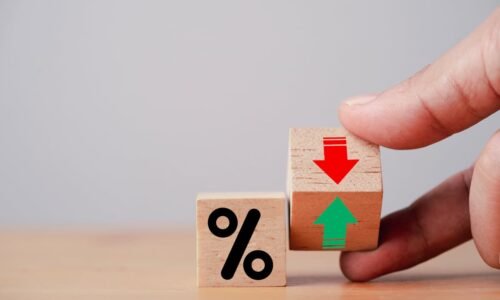 Beside a wooden block that shows a percent sign, a hand holds a second wood block that shows a green arrow point up and a red arrow pointing down.