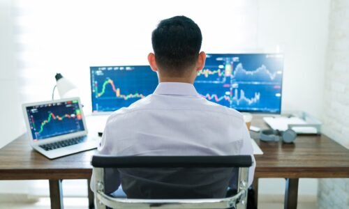 Person working at desk with multiple monitors.