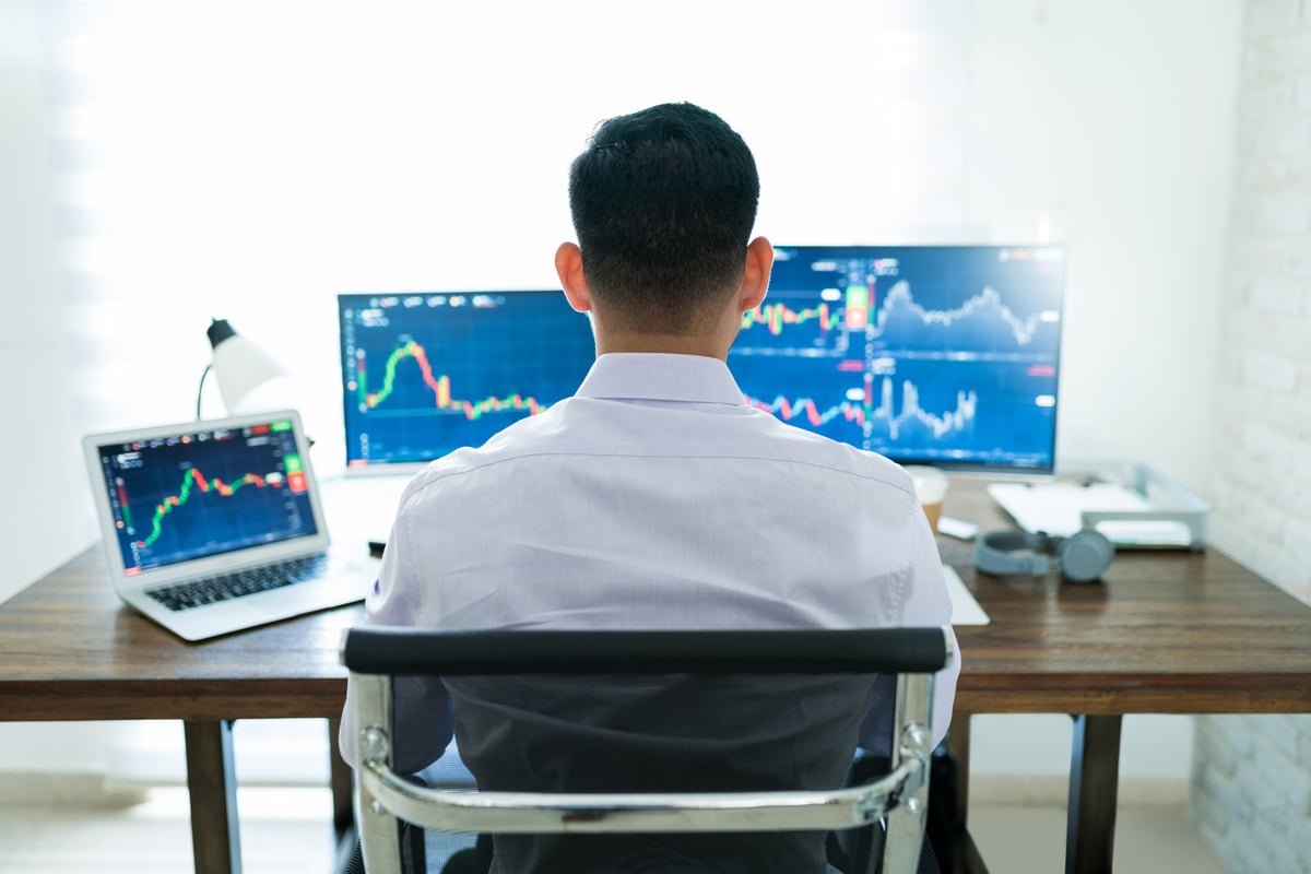 Person working at desk with multiple monitors.