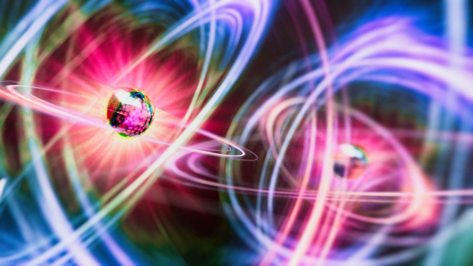 An illustration of two particles as glowing geodesic shapes surrounded be halos of pink, yellow and blue light