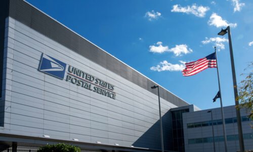 Exterior of a United States Postal Service building with an American flag flying