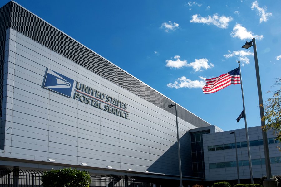 Exterior of a United States Postal Service building with an American flag flying