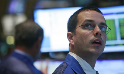 A trader looking up at stocks on a video screen.