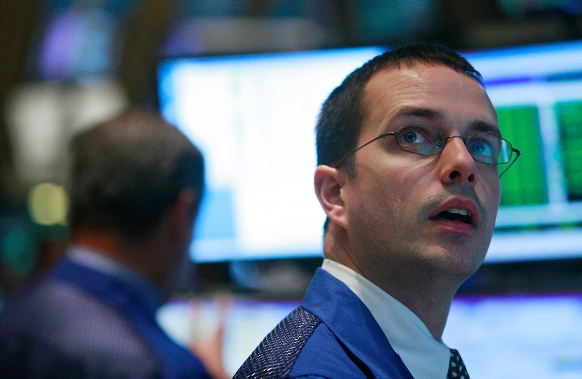 A trader looking up at stocks on a video screen.