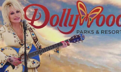 Dolly Parton holding a guitar with the 'Dollywood Parks & Resorts" logo in the background