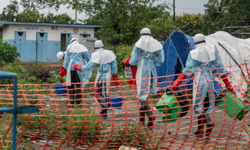 Health workers in full protective gear entering an Ebola treatment center in Rwampara, Congo.