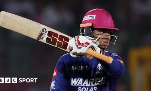 Vaibhav Sooryavanshi holds his bat aloft after passing 50