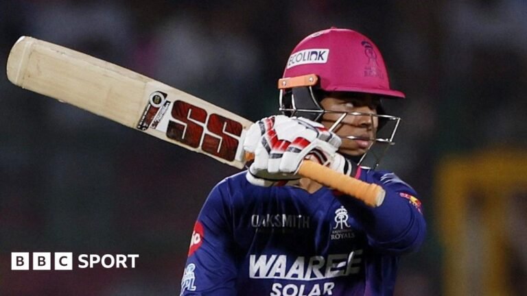 Vaibhav Sooryavanshi holds his bat aloft after passing 50