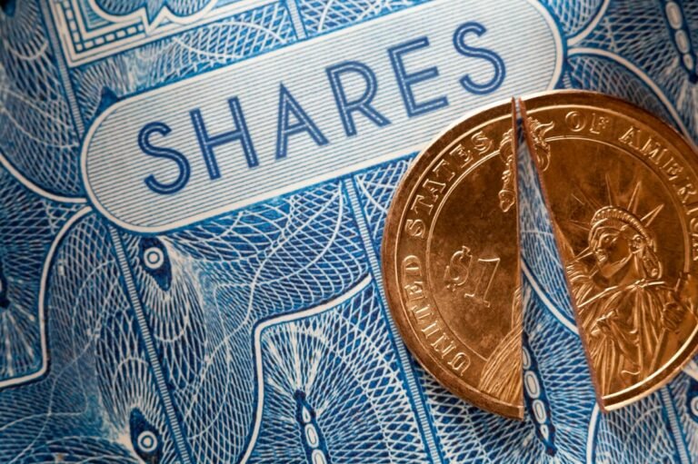 A U.S. dollar coin split in half that's been placed atop a paper stock certificate for shares in a public company.