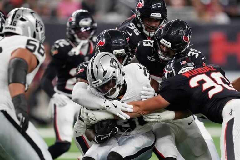 Las Vegas Raiders running back Mike Washington Jr., center, is stopped on a run against the Hou ...
