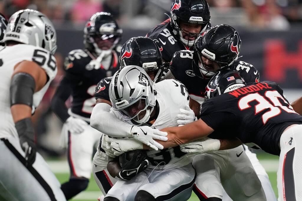 Las Vegas Raiders running back Mike Washington Jr., center, is stopped on a run against the Hou ...
