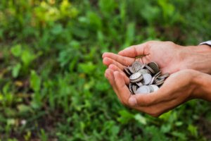 Mãos em concha segurando amontoado de moedas