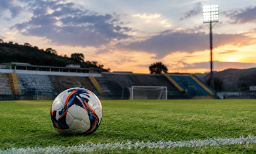 Estádio Soares de Azevedo vazio, com campo iluminado e elementos simbólicos do Nacional de Muriaé.