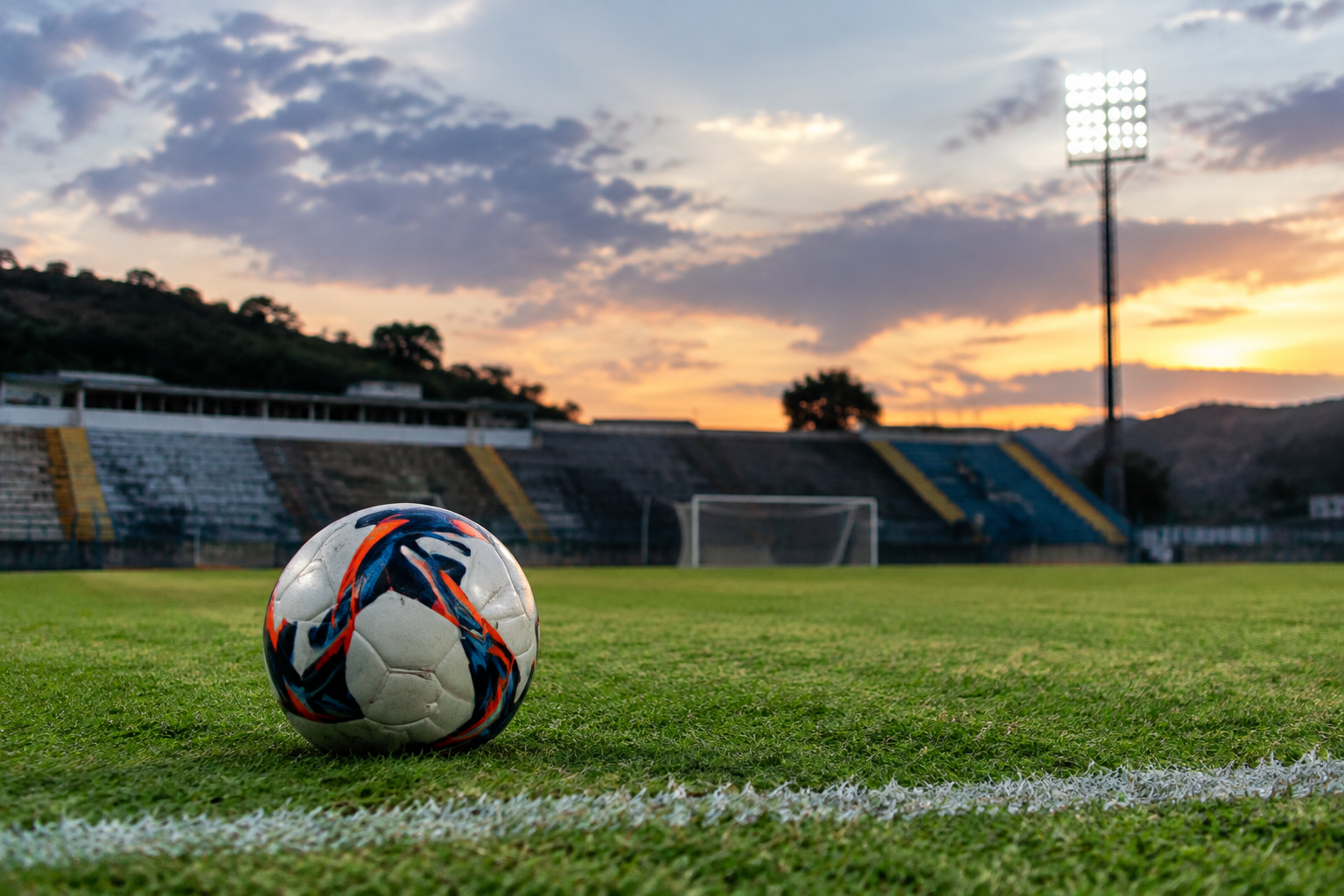 Estádio Soares de Azevedo vazio, com campo iluminado e elementos simbólicos do Nacional de Muriaé.